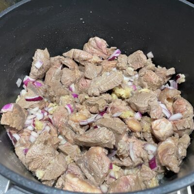 Onions and garlic added to brownish Beef cubes for Filipino Beef Pochero recipe