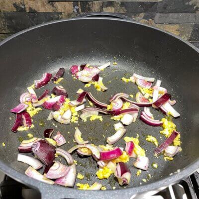 Add-Red-Onions-to-fried-garlic-in-pan-cooking-a-kare-kare-recipe