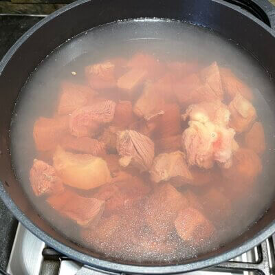 Boiling-beef-in-2.5-liters-water-for-cooking-a-kare-kare-recipe