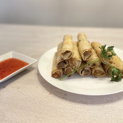 Filipino Lumpia Shanghai on a white plate with Sweet Chili sauce at the side