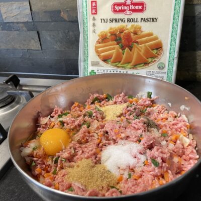 Spices and egg added for Shanghai Spring Rolls in big bowl with Lumpia wrapper at the back