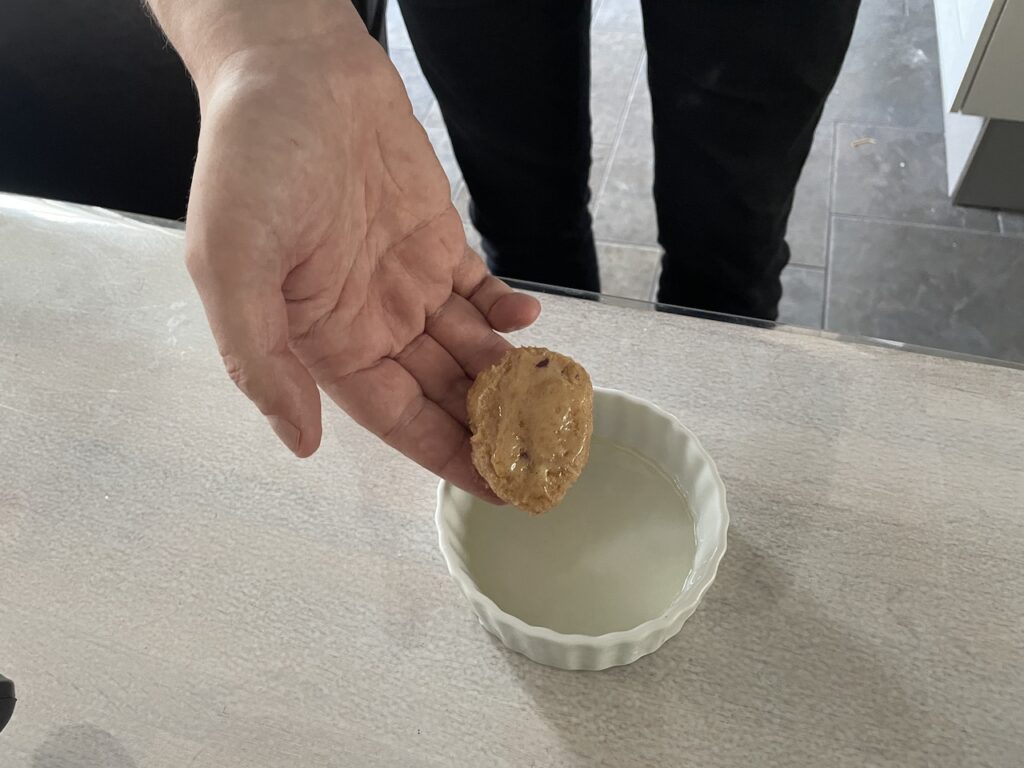 Hands shaping the chicken mixture into nugget-sized pieces and placing them on a parchment-lined tray.